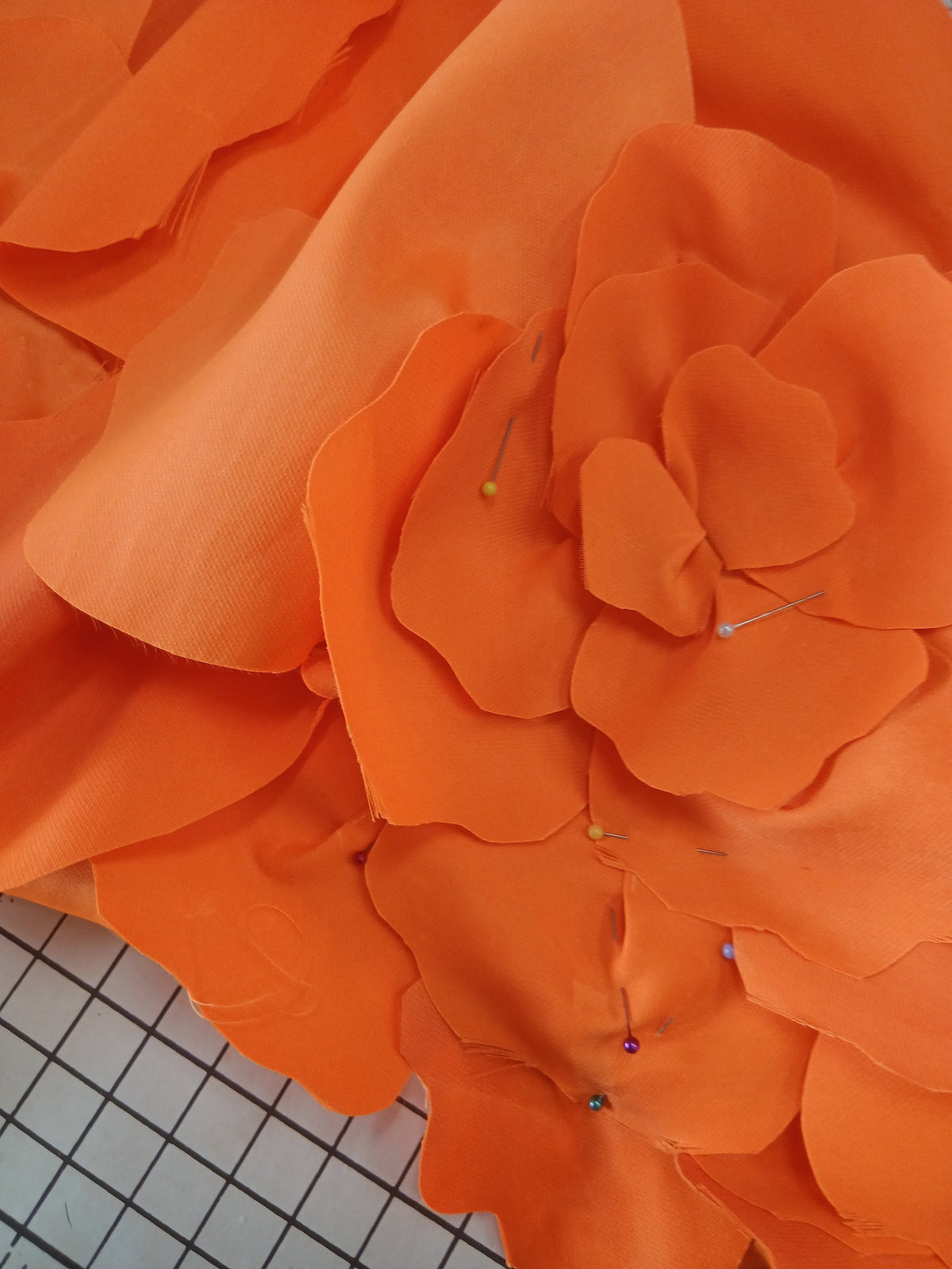 Orange chiffon petals cut and pinned on the cutting mat while a gown is being made